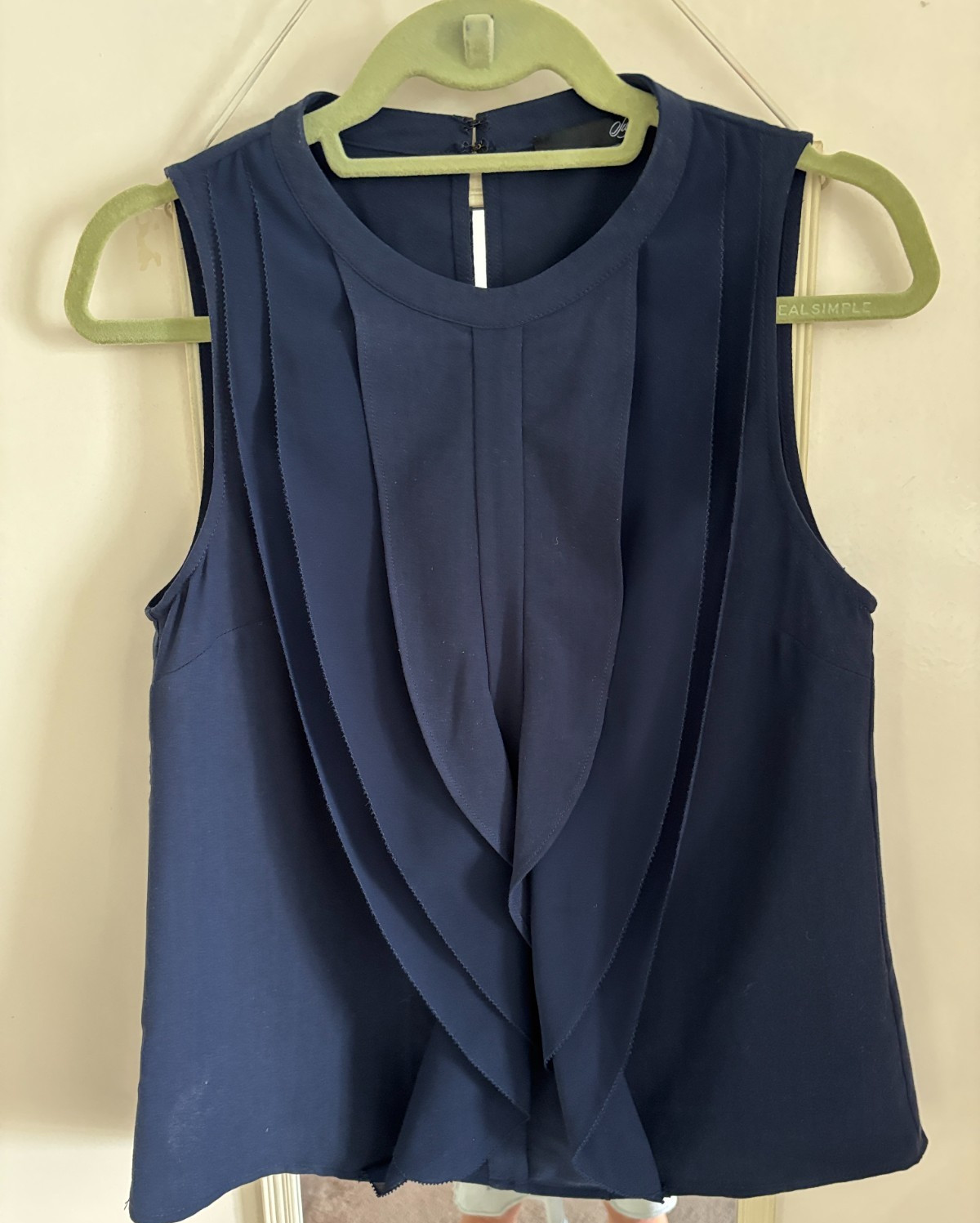 A sleeveless Navy blue blouse virtical fruffles the front
